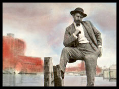 A dapper man standing near a waterfront.
