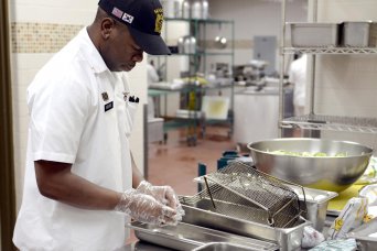 Sgt. Marques Moore, a Tampa, Fla., native, and food service specialist with the 2nd Battalion, 9th Infantry Regiment, 1st Armored Brigade Combat Team, prepares some onions for a dish in the kitchen of the Iron Caf&#233; during its reopening ceremony. The ceremony commemorated the consolidation of the two dining facilities on Camp Hovey.  (U.S. Army photo by KATUSA Pvt. Kwon Yong-joon, 1ABCT PAO)