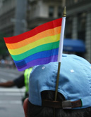Photograph of a person wearing a baseball cap with a rainbow flag in it.