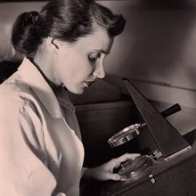 photo of Dr. Ruth Kirschstein looking into a microscope.