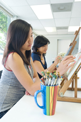 Una joven adolescente pinta en un lienzo.
