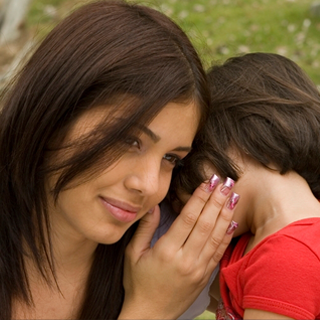 Mother listens to daughter tell a secret in her ear