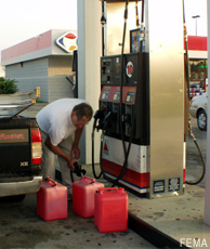 Photograph of a man filling gasoline containers at a gas station