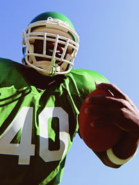 A football player in a green jersey holding a football.