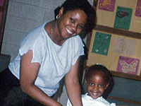 A smiling woman and child standing together in a classroom