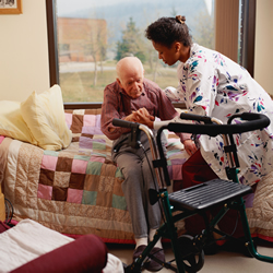 nurse aids patient trying to stand from a seated position