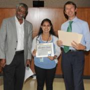 Two adults presenting and award to a teenage girl.