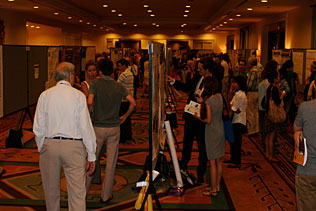 Many people walking in and around poster boards during the poster session.