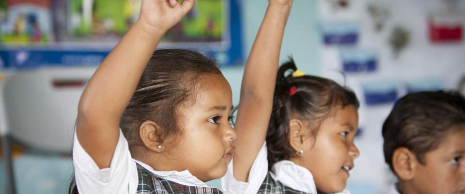 Young girls in Honduras raise their hands in class. USAID/Honduras