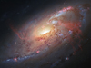 Dazzlingly complex galaxy with a golden, glowing center, blue-white spirals, sporadic pink blossoms of stars, dark filament lanes and rust-red streaks cutting across the spirals