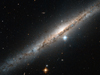 A bend sinister of a side-on galaxy, showing a central dark dust lane and several bright stars shining through