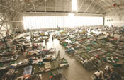 Cots and people inside a large airplane hangar