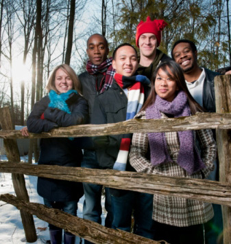 A diverse group of young people standing at a fence.