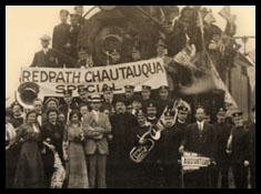 Group of people posed in front of a train, with a sign reading "Redpath Chautauqua Special"