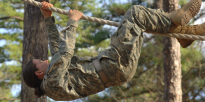 Female soldier on inverted rope obstacle