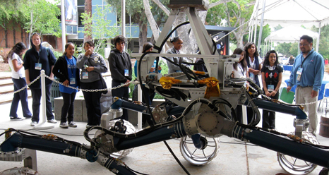 Students watch an engineering model of the Mars Science Laboratory maneuver over simulated Mars rocks