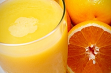 A glass of orange juice next to oranges