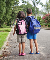 A boy and a girl child in a residential area standing looking down the road