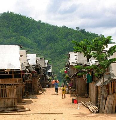 Picture of man walking through village with bamboo covered huts