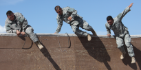Soldiers jumping from wall on obstacle course
