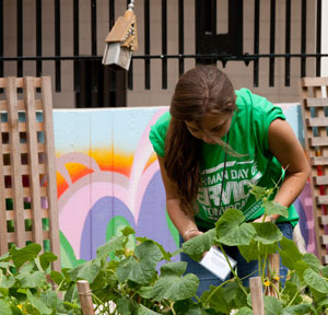 Photograph of a young woman working on a garden project and wearing a Day of Service t-shirt.