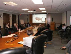 Photograph of attendees viewing maps that are being displayed on a projection screen.