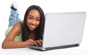 Photograph of a teen girl using a laptop computer.
