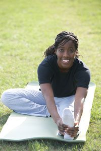 Photograph of a young woman smiling and doing yoga.