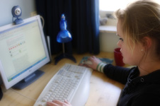Una niña mirando la pantalla de una computadora y usando una cámara web