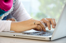 Up-close view of a woman’s hands typing on a laptop keyboard