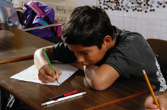 Boy writing or drawing on a piece of paper.