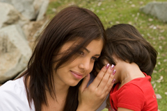 Una madre escucha a su hija decirle un secreto al oído