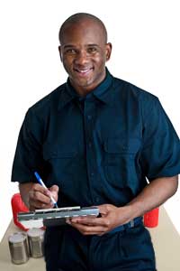 A man stands in front of a table full of disaster supplies, making a checklist.