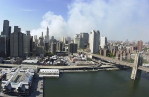 Profile of New York City buildings, smoke is billowing above them from the collapse of the twin towers