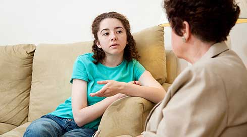 A photo of a teen talking with her therapist