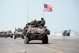 U.S. Marines roll into Kuwait International Airport in light armored vehicles after the retreat of Iraqi forces from Kuwait during Operation Desert Storm.  At right is a CH-53 Sea Stallion helicopter. (by McLeod; David/Tech. Sgt.)
