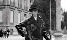 Helen Clay Frick standing, wearing black trench coat, in Belgium.