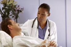 Fotografía de una doctora hablando con un paciente acostado en una cama de hospital