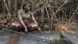 A woman coated in oil perches near a mangrove after fishing in a creek near the River Nun in Nigeria's oil state of Bayelsa, November 27, 2012.