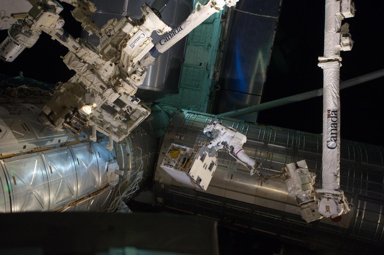 Image description: Spacewalker Mike Fossum rides on the International Space Station&#8217;s robotic arm as he carries the Robotic Refueling Mission experiment. This the final scheduled spacewalk during the Atlantis shuttle mission.
Photo by NASA