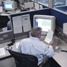 Man reading over a report by his desk and computer