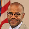 Photograph of Commissioner Bryan Samuels in front of a U.S. flag.