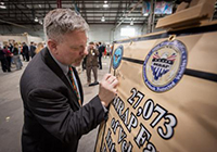 David Hansen, Joint Program manager, MRAP vehicles writes a message to the integration teams on a commemorative pennant. 