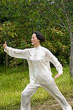 A woman practices Tai Chi outside.