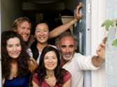 A diverse group of people welcomes someone to the front door.