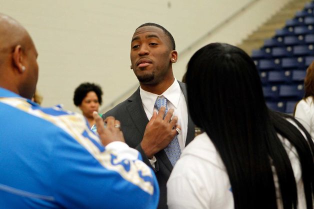 Fort Bend Marshall linebacker Deon Hollins Jr. straightens his tie next to step-father, Frank Satcherwhite, and mother, Natoya Satcherwhite, as he made his commitment to UCLA during a signing day ceremony at the Buddy Hopson Field House Tuesday, Feb. 5, 2013, in Missouri City. Photo: Johnny Hanson, Houston Chronicle / © 2013  Houston Chronicle