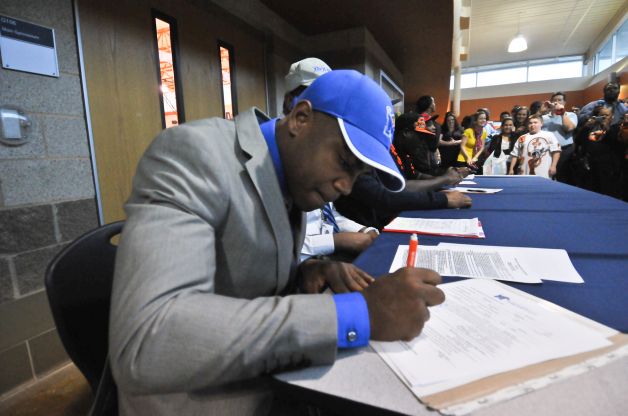Madison High School football player Marquis Warford signs his scholarship to the University of Memphis during a National Signing Day ceremony at the school Wednesday. Photo: Robin Jerstad
