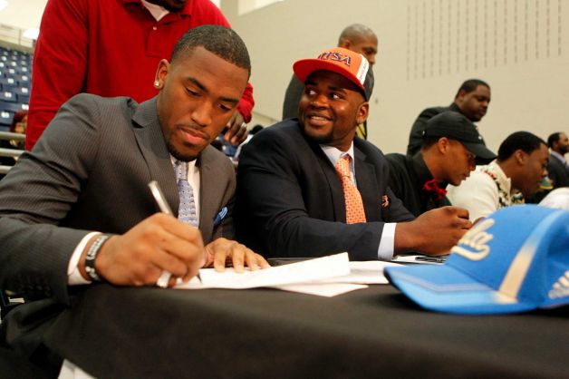 Fort Bend Marshall linebacker Deon Hollins Jr., left, signs during a mock commitment letter to play football at UCLA, next to  teammate Anthony Lee who committed to the University of Texas San Antonio during a signing day ceremony at the Buddy Hopson Field House Tuesday, Feb. 5, 2013, in Missouri City. Photo: Johnny Hanson, Houston Chronicle / © 2013  Houston Chronicle
