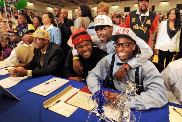 Dorian Killings, second from right, who is already enrolled at Central Florida,  joined teammates De'Asian Richardson, center, who signed with the University of Louisville and Tyrell Lyons, right, who signed with Florid State during National Signing Day ceremonies at First Coast High School, Wednesday, Feb. 6, 2013, in Jacksonville, Fla.  14 Students from First Coast High School in Jacksonville, Florida signed their letters of intent to play sports for a range of colleges during a rally in the school's gym.  T(AP Photo/The Florida Times-Union, Bob Self) Photo: Bob Self, Associated Press / The Florida Times-Union