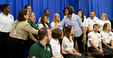 Photograph of First Lady Michelle Obama shaking the hand of an Americorps leader, in a group of corps members.  Photograph courtesy of the Corporation for National and Community Service.
